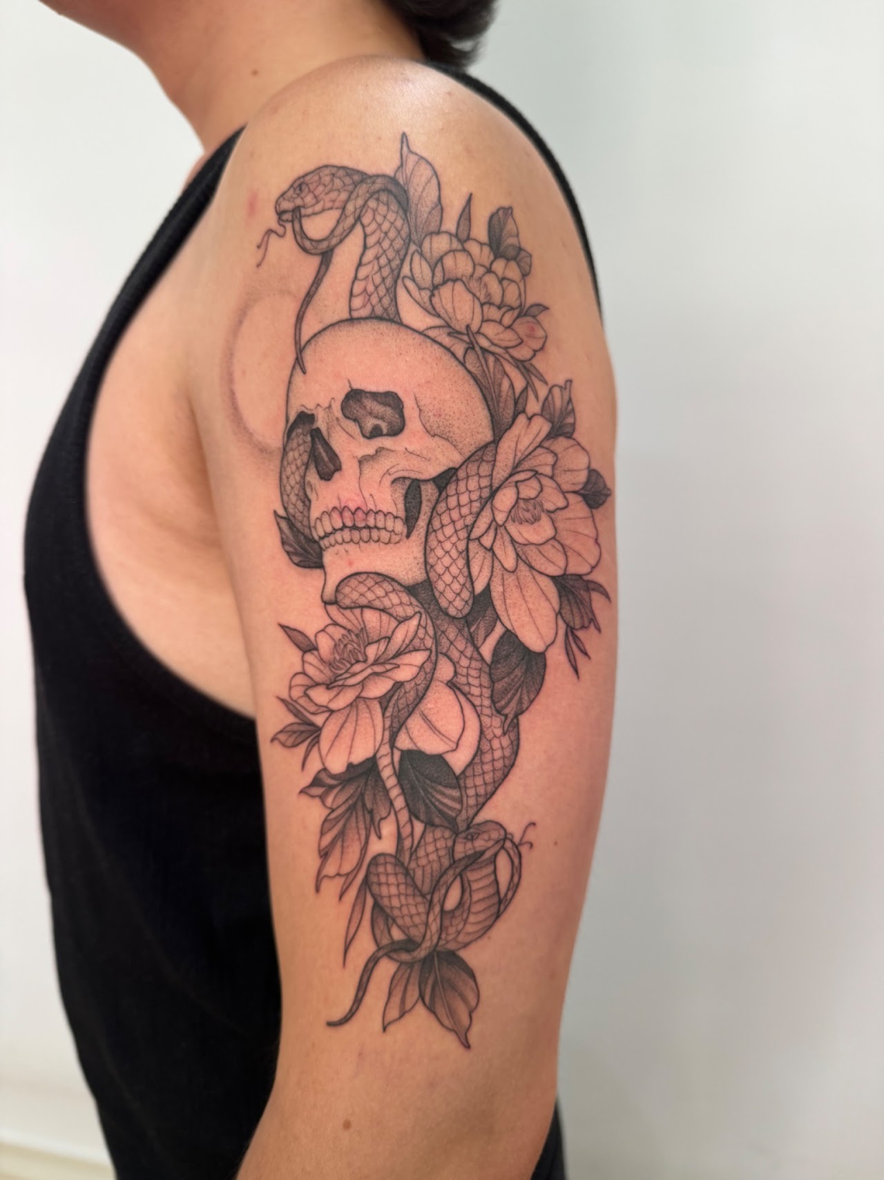Tatuaje Cráneo con serpiente y flores blackwork — CAOS Art Tattoo Chile