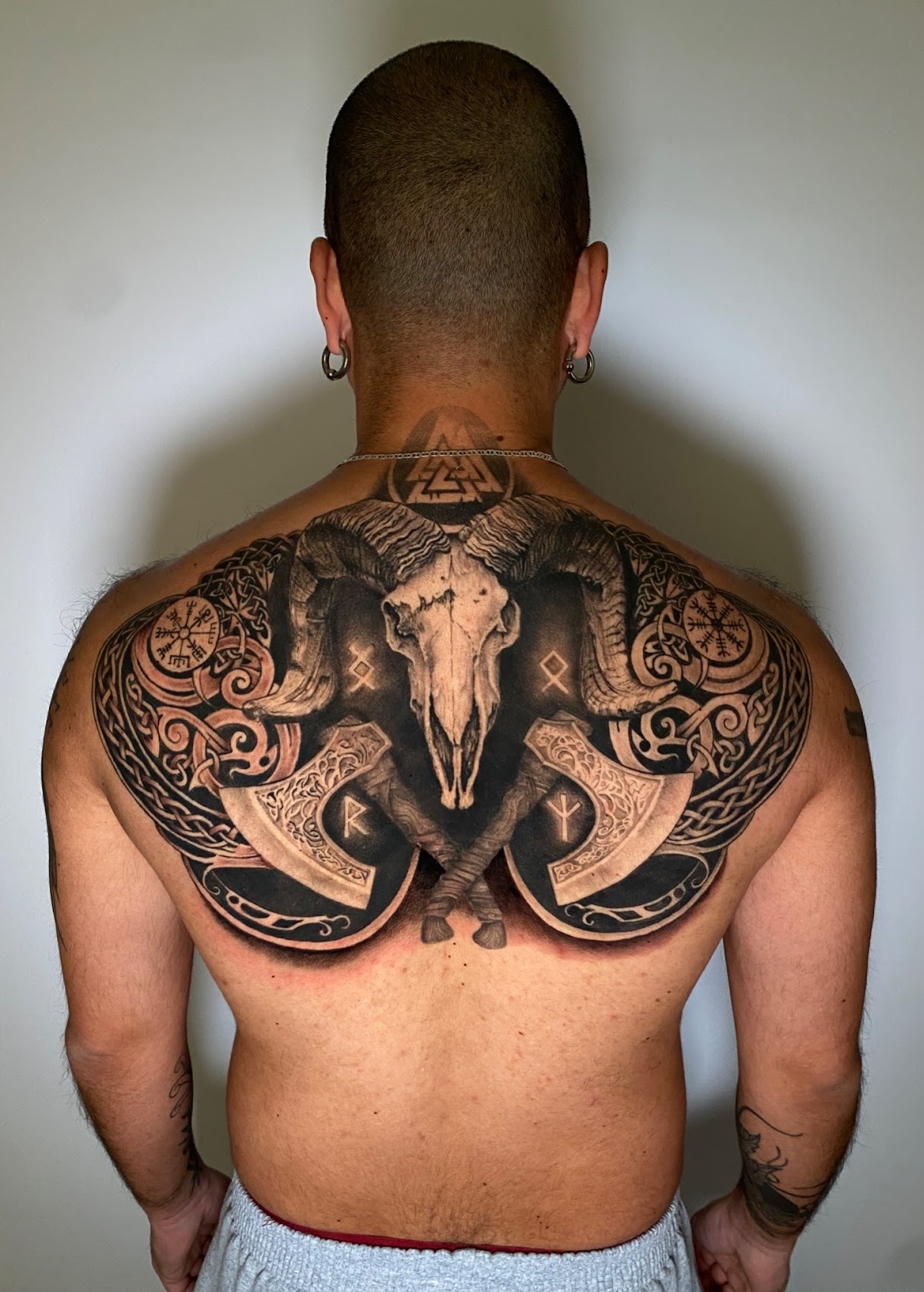 Tatuaje Cráneo carnero con hachas vikingas y runas espalda — CAOS Art Tattoo Chile